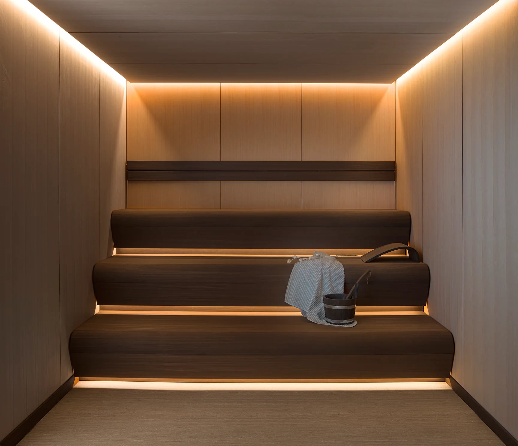 INFINITY Sauna craftsmanship with shaped timber benches, fitted lighting and a wooden bucket